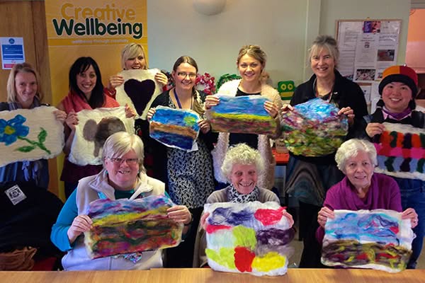 Happy female group showing off their colouful felt landscapes