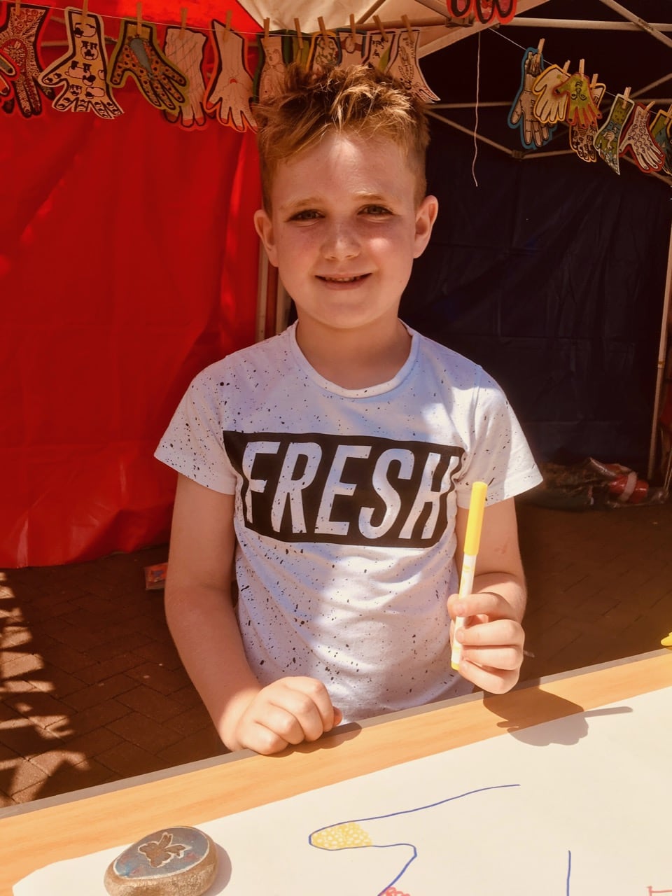 Young boy enjoying drawing in the sunshine at a Creative Wellbeing event in Cartlisle city centre